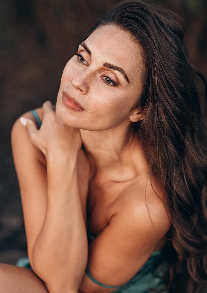 Melbourne facial cosmetic surgery model with long hair posing thoughtfully outdoors.