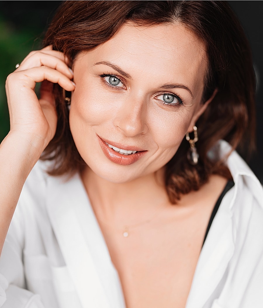 Smiling Melbourne facial cosmetic surgery model with blue eyes and elegant earrings.